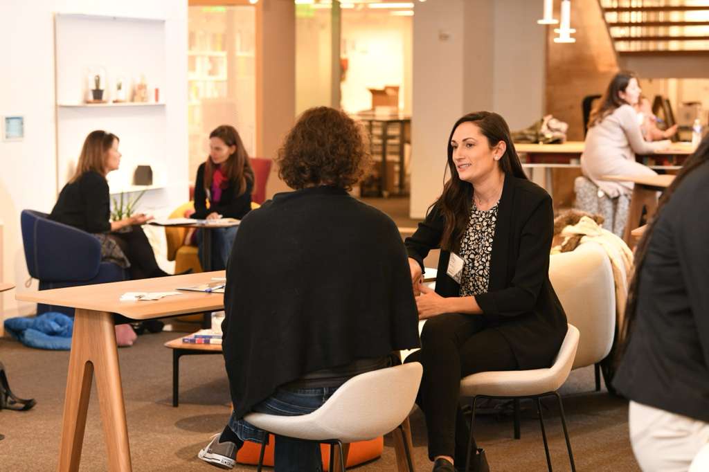 Woman and man having a serious conversation on a couch while a therapist takes notes in a bright room.